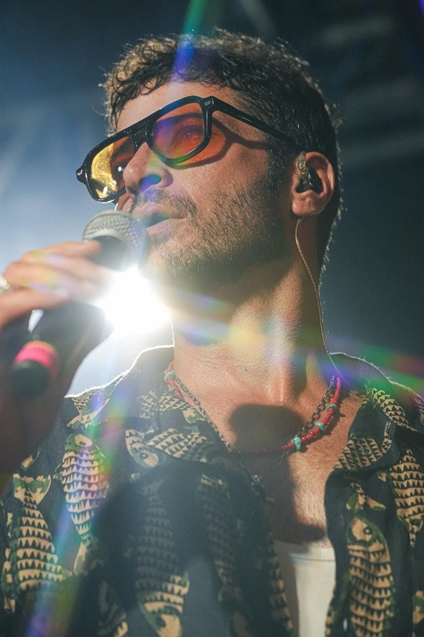 Leandro Lima cantando ao microfone sob a luz do palco